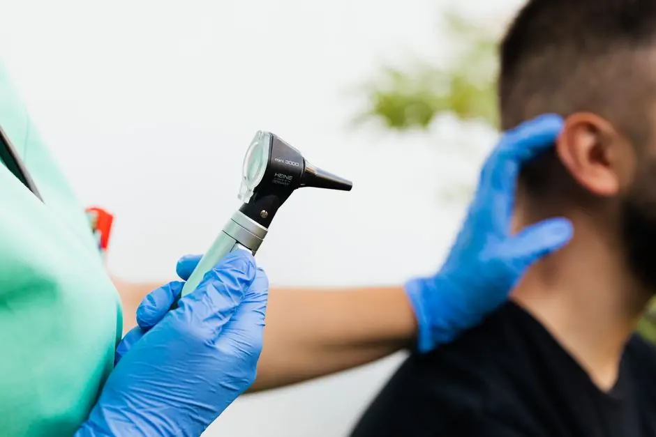Healthcare professional examining patient’s ear with an otoscope in a clinical setting.